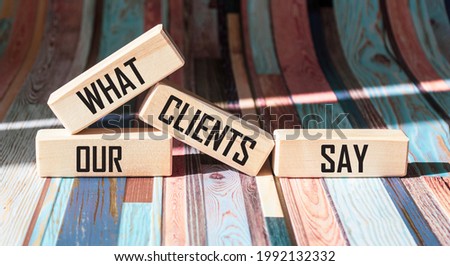 What our customers say, text on wooden blocks and colorful background Royalty-Free Stock Photo #1992132332