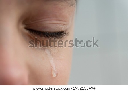Close up image of teardrop rolls down the boy's cheek, his eyes are closed, he is upset and crying. Sad, unhappy emotions of child. Royalty-Free Stock Photo #1992135494