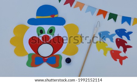 Clown, ball to play in the clown's mouth, toy fishing and colorful flags. White background. One of the traditions to brighten up the Brazilian June party is the Boca do Palhaço and Toy Fishing games.