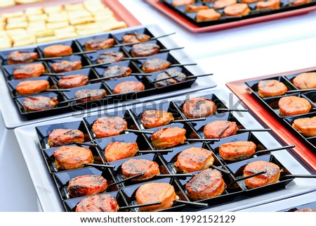 Catering fingerfood closeup. small backed oriental snacks on square black plates with tiny spoons. Gourmet food degustation. Menu concept picture. Healthy dieting. corporate party snacks