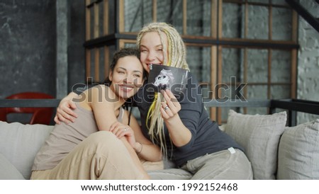Pregnant lesbian couple showing ultra sound image in bedroom