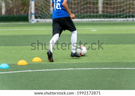 Asian teenager Football Players In Blue practicing football at the training ground