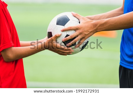 Asian teenager Football Players fair play handed a soccer ball to his brother Royalty-Free Stock Photo #1992172931