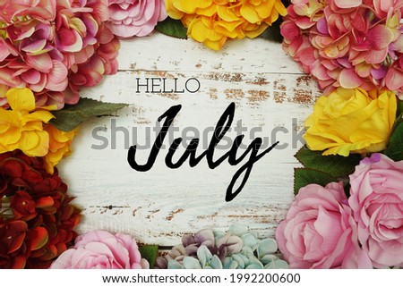 Hello July text and Flowers Colorful Border Frame on wooden background