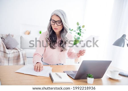 Photo of focused serious old woman look table paper documents laptop job indoors inside house home flat