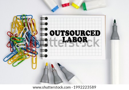 Business and finance concept. On the table are markers, paper clips and a notebook with the inscription - Outsourced Labor