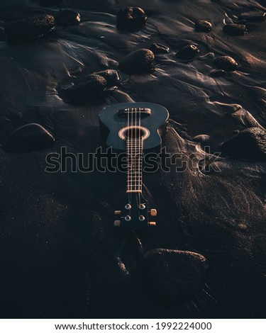 this image is captured to show white and black guitar on black sand.