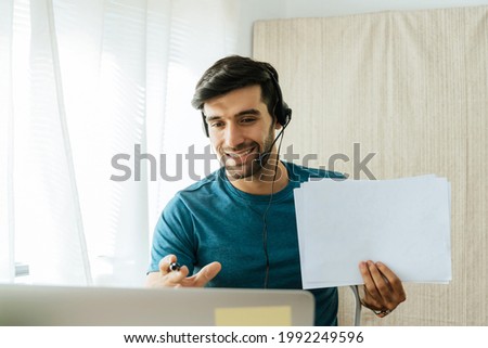 Education online. handsome man teacher with headset showing blank paper sheet for teaching online at web camera on laptop computer, education, online learning, social distancing, internet concept