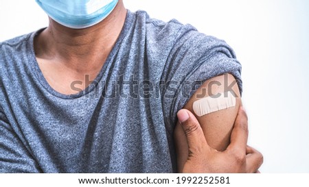 Man putting adhesive bandage plaster medical on man'arm after injection of COVID'19 CORONA Vaccine.