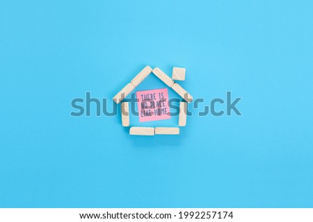 Small house made of wooden blocks and a sticky note with handwritten text There is no place like home