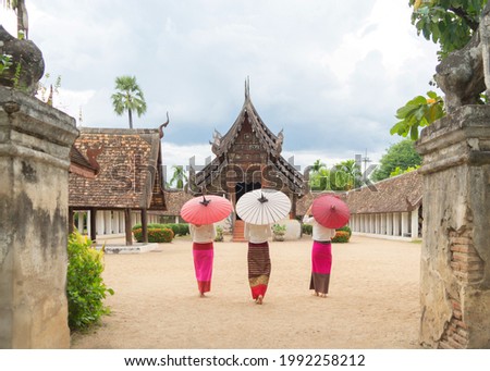 Portrait of group of Asian Shan women girls, Tai Yai, northern Thai people holding an umbrella with traditional Lanna clothes at Wat Ton Kwen temple, decoration. Culture lifestyle. Royalty-Free Stock Photo #1992258212