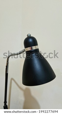 A black work lamp that has started to rust and is dusty because it has not been used for a long time.
