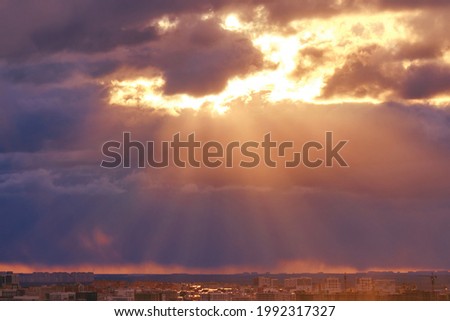 Dark clouds in the red evening sky with the rays of the sun, sunset background
