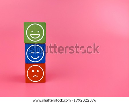 An image of emoticon of happy and sad on a wooden block.