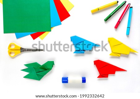 Colorful origami paper parrots, white background . children's creativity