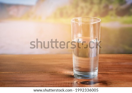 water in a glass on a wooden table outdoors.