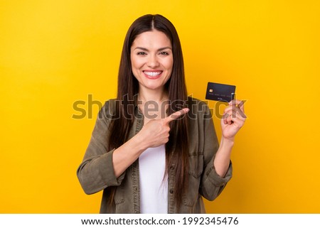 Photo of charming cheerful young woman point finger credit card pay money sale isolated on yellow color background