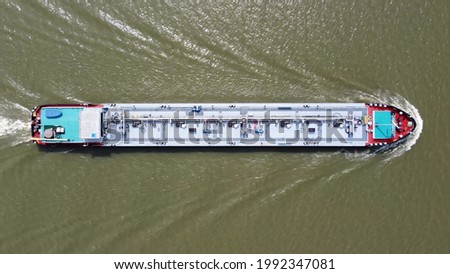 Aerial top down view of tank barge is vessel that is used to carry liquids solids and gas through waterways and rivers and across areas of ocean an essential player in energy and offshore industries Royalty-Free Stock Photo #1992347081
