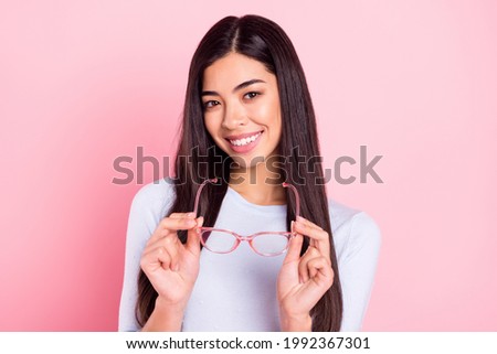 Portrait of attractive cheerful shy cute modest girl holding in hands specs posing isolated over pink pastel color background Royalty-Free Stock Photo #1992367301