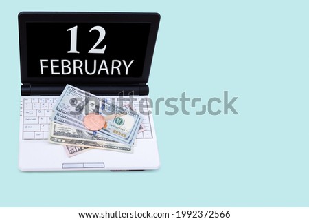 12th day of february. Laptop with the date of 12 february and cryptocurrency Bitcoin, dollars on a blue background. Buy or sell cryptocurrency. Stock market concept. Winter month, day of the year