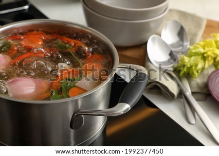 Pot of delicious vegetable bouillon on stove in kitchen, closeup