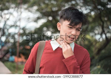 A young male call center agent or teacher tries to soothe his scratchy throat. Sore or dry throat caused by fatigue or disease. Royalty-Free Stock Photo #1992388877