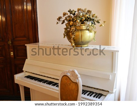 Snow-white grand piano with a golden vase of flowers