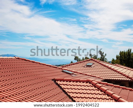 Modern house , red clay tiled roof, rain gutter and gable and valley type of roof construction. Roofing Construction. Royalty-Free Stock Photo #1992404522