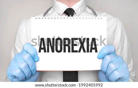 Medical concept. Doctor is writing the word anorexia on white paper notepad