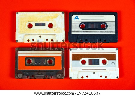 Four Old Audio Cassettes on the Red Paper Background closeup