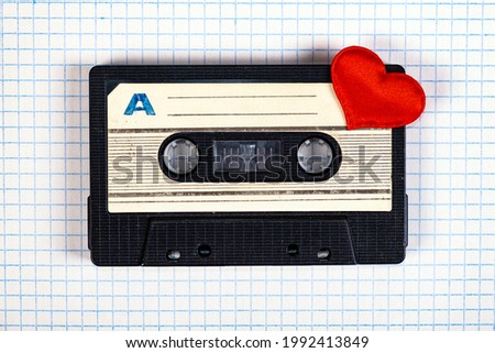 Old Audio Cassette with a Red Heart on the Square Paper Background closeup
