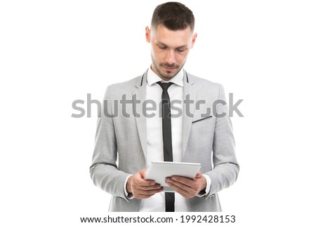 Horizontal medium portrait of handsome young adult Caucasian man wearing elegant suit using digital tablet for work, white background