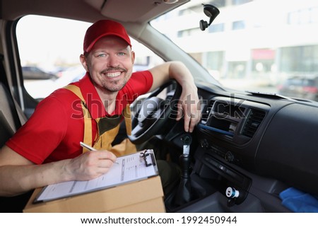 Smiling courier with clipboard on the driver seat of car