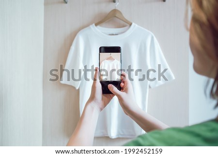 Woman is taking photo on smartphone of used clothing for resale or charity
