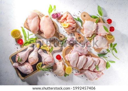 Various raw chicken meat portions. Set of uncooked chicken fillet, thigh, wings, strips and legs on white cooking table background with spices  Royalty-Free Stock Photo #1992457406