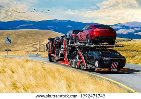 Car carrier. New, expensive cars, transported on the platform. the price of cars- concept. No logo or brand. Royalty-Free Stock Photo #1992471749