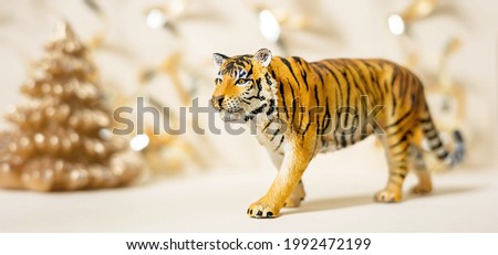 Tiger symbol of the Chinese new year 2022. Figurine of tiger with golden christmas fir tree on pastel background. Copy space, banner