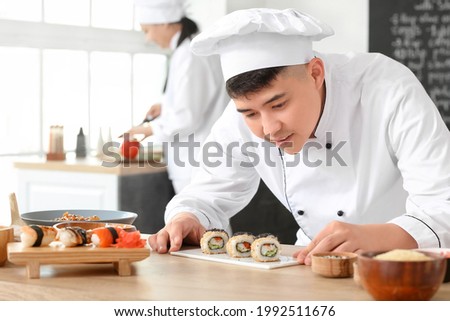 Handsome Asian chef cooking in kitchen