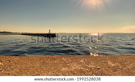    blue sea water wave at sunset yellow cloudy sky reflection on water splash stone pier sun down evening on Baltic sea