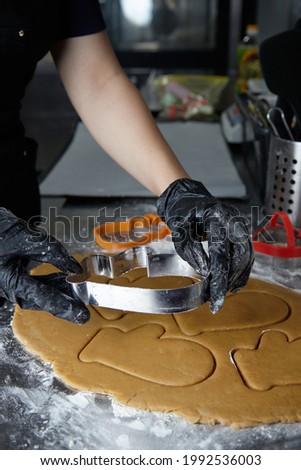 cook with gloved hands makes cookies using a dough mold