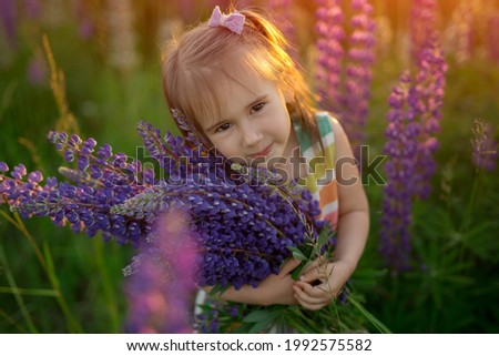 A beautiful little girl holds a bouquet of purple flowers for her mother. Children's Day. 