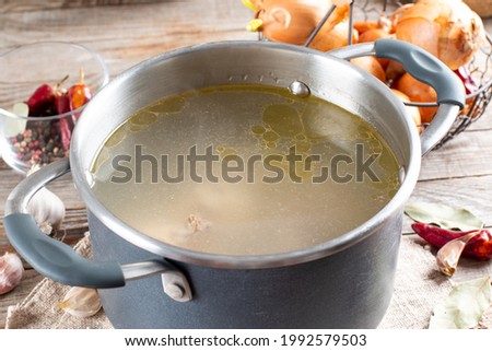 Bone Broth Bouillon in Metal saucepan on the wooden table, paleo diet