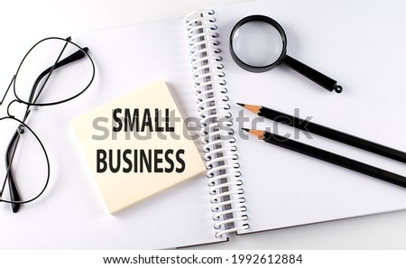 Word SMALL BUSINESS on the sicker on the notebook with pencils,magnifier and glasses