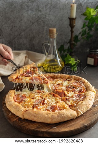 selective focus. hot pizza with cheese and pepperoni. the girl pulls a slice of pizza with melted cheese stretching. vertical position, dark mood