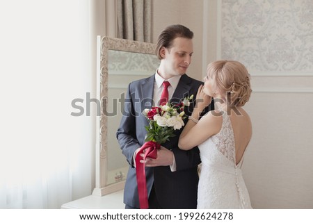Wedding morning of the bride and groom in luxury classic interior. Pretty young couple in elegant wedding clothes tenderly hugging each other in royal room of hotel. Wedding day ceremony. Young family