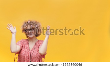 Beautiful girl enjoying her favorite music through her headphones. Girl in a good mood wearing round spectacles and enjoying with eyes closed. Isolated on bright yellow background. Music Lover.