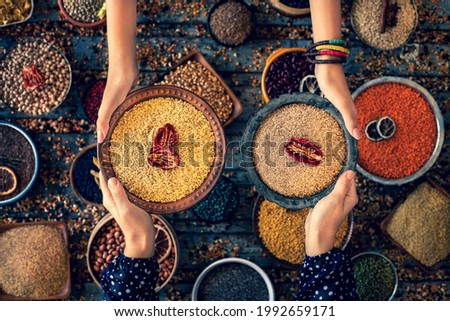 Bulgur wheat at the hands of two women in the bowl. Royalty-Free Stock Photo #1992659171