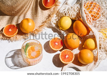 Summer fashion flat lay on white background. Holiday party, vacation, travel, tropical concept. Straw hat, refreshing drinks and citrus fruits. Palm shadow and sunlight, sun. Top view Royalty-Free Stock Photo #1992708305
