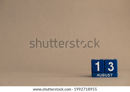 Date 13 August on blue dice on a beige eco-background