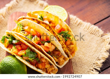 Taco with meat and vegetables on sackcloth. Mexican tacos and limes on wooden boards. Taco with meat, tomatoes and herbs. Rustic style